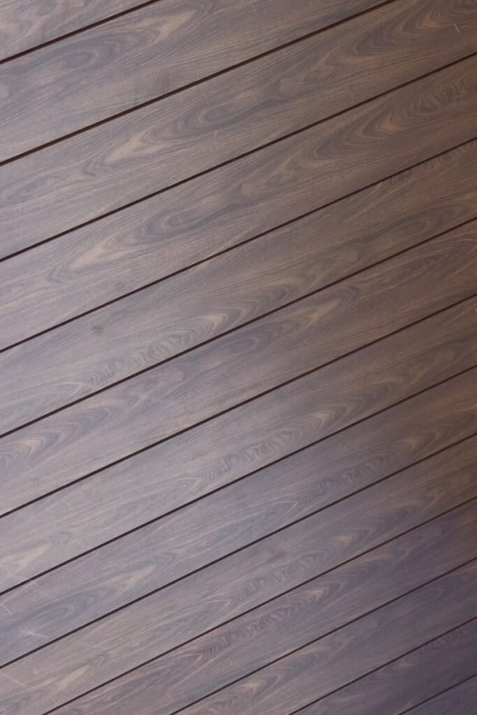 Diagonal close-up of installed Dark Brown Aluminum Siding planks with a deep wood-grain texture and visible seams.